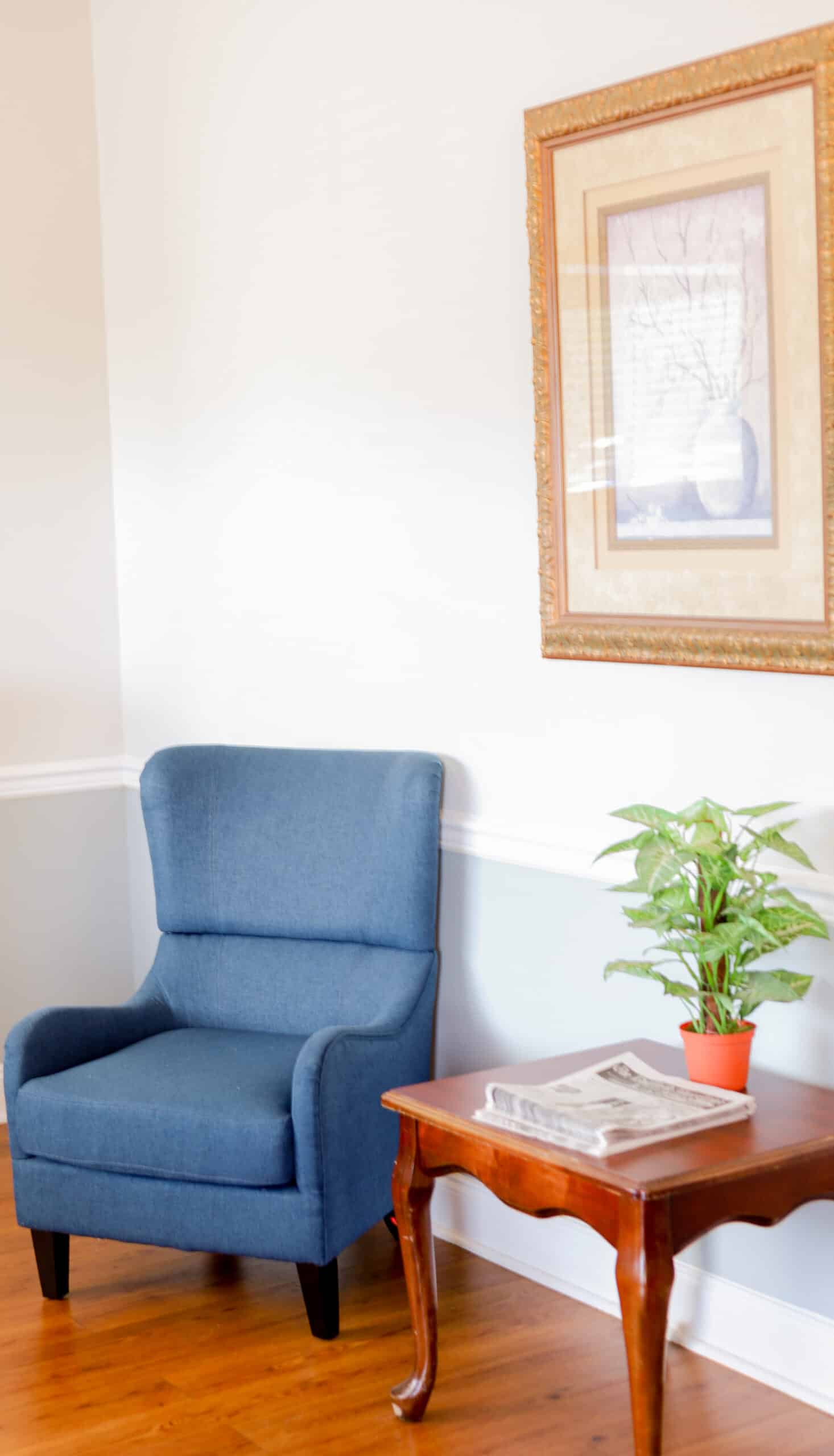 Chair and end table with a painting on the wall
